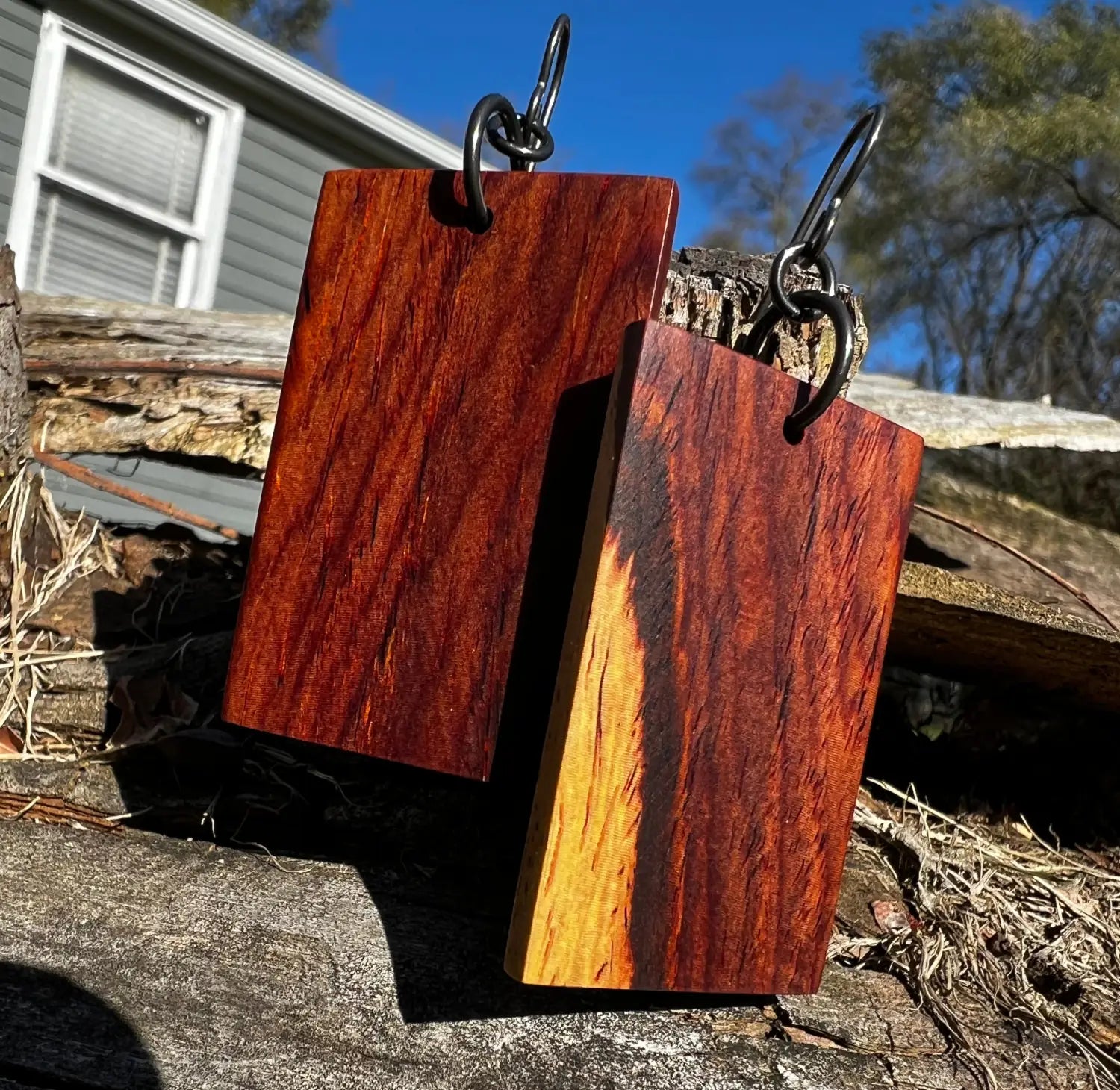 Cocobolo earrings displayed on a old log